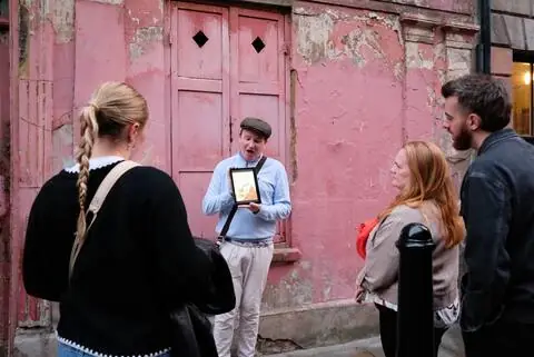 A guide holding up an old photograph for the group