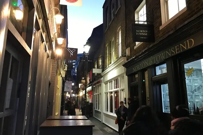 A narrow East End lane lit by lamps in the evening